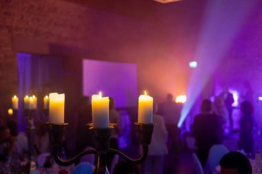 Zarif masalarda mumlar titreşiyor, konuklar güzel aydınlatılmış bir mekanda kaynaşırken sıcak bir parıltı saçıyor. Renkli ışıklar neşeli bir toplanma için neşeli bir atmosfer yaratır..