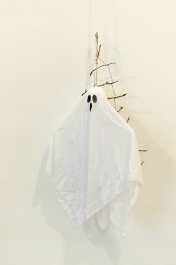 A white ghost made from fabric hangs from a branch. This decoration adds a spooky touch to the room, perfect for Halloween festivities.