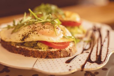 Bu nefis branç yemekleri kremalı avokado, taze domates ve yumurtalarla kızartılmış ekmek, roka ve balzamik yağmurla süslenmiş, hafta sonu yemeği için mükemmel..