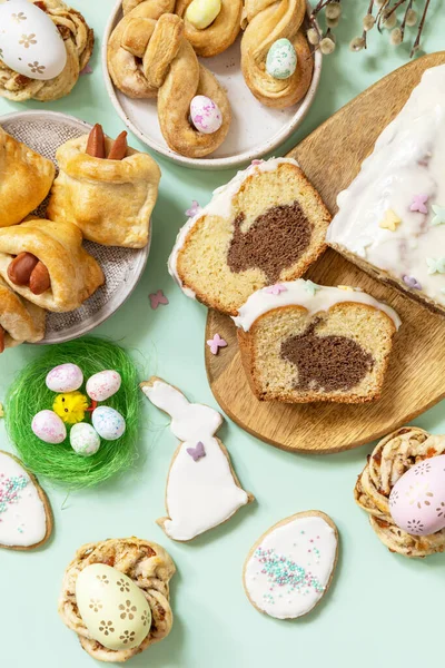 Festive dinner, Easter brunch. Happy Easter holiday food baking puff pastry and cupcake with Easter Bunny on pastel green background. View from above.