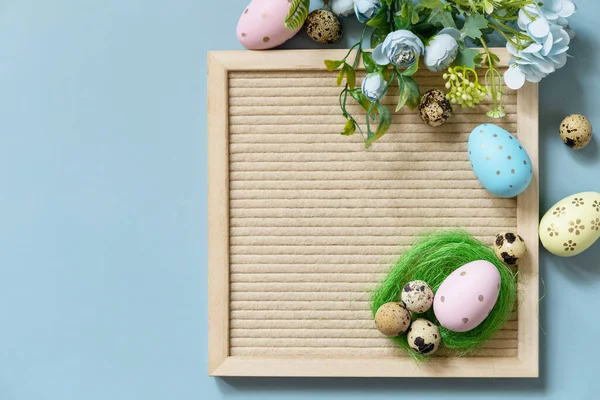 Springtime welcome concept. Letter board, Easter eggs and spring flowers on a pastel blue background, minimalism style composition. View from above. Copy space