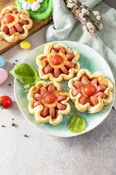 Idea for Easter breakfast or lunch. Mini pizza. Pizza in puff pastry with cheese and tomatoes on the festive table. Copy space.