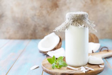Vegan sütsüz alternatif süt, sağlık içeriği. Kırsal bir masada şişedeki organik hindistan cevizi sütü. Boşluğu kopyala.