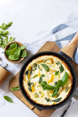 Ispanaklı ve peynirli omlet. Yumurta, paprika ve ıspanaktan yapılmış Frittata mermer bir tezgahın üstünde kızartma tavasında. Yukarıdan bak. Boşluğu kopyala.