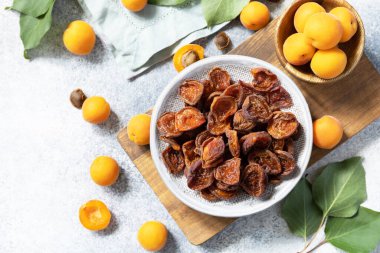 Kurutulmuş meyve ya da şekerli meyve. Gri bir arka planda kurumuş kayısılar ve çiğ kayısılar. Yukarıdan görüntüle.