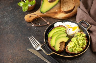 Sağlıklı kahvaltı konsepti, avokado ve yumurtalı sandviç. Avokado dilimlenmiş ekmekli tost ve arka planda haşlanmış yumurta. Boşluğu kopyala. 