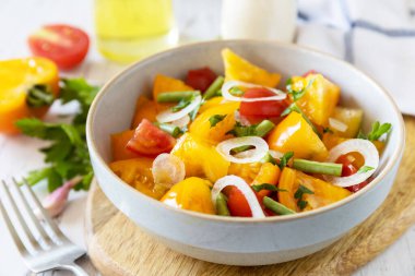 Vejetaryen ya da diyet yemeği kavramı. Ahşap bir masada kırmızı ve sarı domates ve yeşil fasulye karışımından yapılmış domates salatası.. 