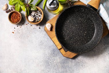 Empty skillet, vegetables, spices and herbs on gray stone background. Food cooking background with Frying pan. View from above. Copy space.