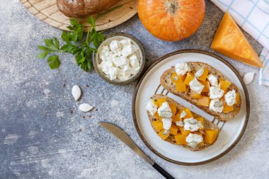 Sandviçleri aç... Baharatlı balkabağı ve peynirli tahıllı ekmeği taş bir masaya koy. Sağlıklı yemekler, vejetaryen aperatifleri. Yukarıdan bak. Boşluğu kopyala.
