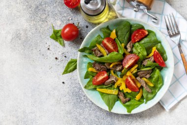 Ispanak salatası, tavuk ciğeri, domates ve baharatlı ızgara biber ve balzamik. Sağlıklı keto diyeti düşük karbonhidrat. Yukarıdan bak. Boşluğu kopyala.