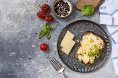 Ev yapımı kahvaltı ya da brunch yemeği, çırpılmış yumurta. Çırpılmış yumurta tam tahıllı ekmeğin üzerinde taş bir masada. Yukarıdan bak. Boşluğu kopyala.