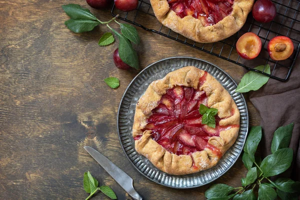 Healthy homemade wholegrain fruit pie, sweet crostata on a rustic table. Vegan vegetarian dessert, plums galette with almonds. View from above. Copy space.