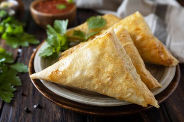 Asya yemekleri. Ahşap bir masada domates soslu vejetaryen samsa (samosa). Endonezya 'da Risoles Sayur Olarak Popüler. 