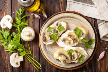 Ev yapımı mantarlı bruschetta. Yumuşak peynirli baget ekmeği ve ahşap kırsal masada ızgara mantarlı sandviç. Yukarıdan görüntüle. 