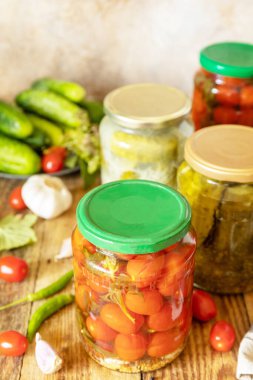 Cam kavanozda saklanmış salatalık turşusu ve domates konservesi. Ev ekonomisi, sonbahar hasat koruma. Sağlıklı ev yapımı mayalanmış yiyecekler..