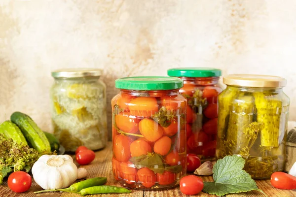 Healthy homemade fermented food. Salted pickled cucumbers and tomatoes preserved canned in glass jar. Home economics, autumn harvest preservation. Copy space.