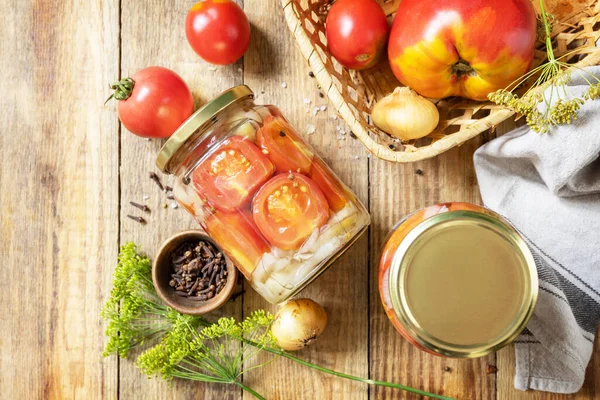 Healthy homemade fermented food. Salted pickled tomatoes and onions preserved canned in glass jar. Home economics, autumn harvest preservation. View from above. Copy space.
