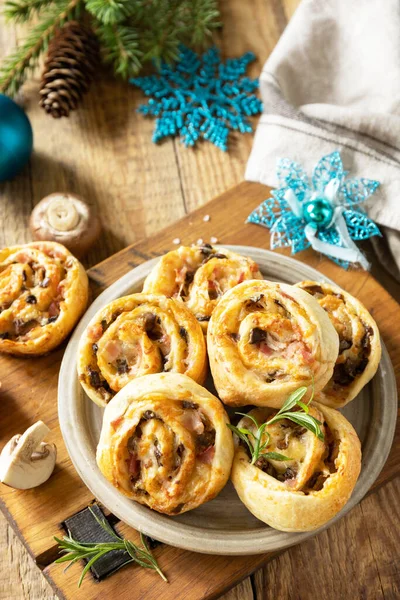 Pizza rolls puff pastry stuffed with prosciutto bacon, mushrooms and cheese on the Christmas table, italian appetizers.
