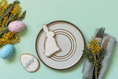 Paskalya yemeği için hazırlanmış masa, paskalya yumurtası ve pastel arka planda mimoza. Paskalya dekorasyonu konsepti. Yukarıdan görüntüle. 
