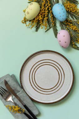 Paskalya yemeği için hazırlanmış masa, paskalya yumurtası ve pastel arka planda mimoza. Paskalya dekorasyonu konsepti. Yukarıdan bak. Boşluğu kopyala.