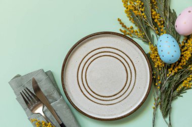 Paskalya yemeği için hazırlanmış masa, paskalya yumurtası ve pastel arka planda mimoza. Paskalya dekorasyonu konsepti. Yukarıdan bak. Boşluğu kopyala.