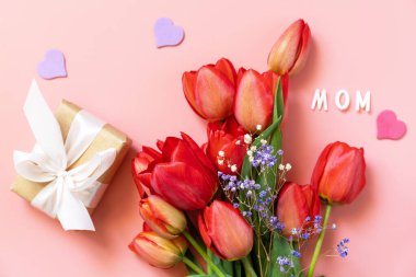 Hediye kutusu olan kırmızı laleler ve küçük kalpler, pastel pembe arka planda boş alan ile yazılmış 