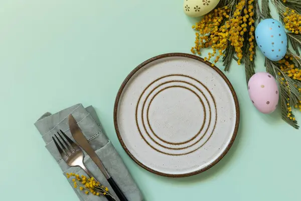 イースターエッグとミモザを背景にイースターディナーのテーブル設定 イースターの装飾コンセプト 上からの眺め コピースペース ロイヤリティフリーのストック写真