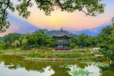 Güney Kore, Seul 'deki Gyeongbokgung Sarayı' ndaki göletin ortasındaki Hyangwonjeong Pavyonu 'nda gün batımı..