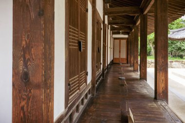 Namsangol Hanok Köyü 'nde geleneksel bir Kore binasının tahta koridoru. Yapıda ahşap kirişler, kafes kapıları ve gölgeli bir yürüyüş yolu bulunuyor. Huzurlu ve kırsal bir atmosfer yaratıyor..