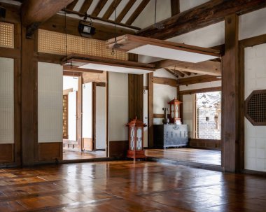 Namsangol Hanok Köyü 'ndeki geleneksel Kore odasında tahta kirişler, sürgülü kapılar, dekoratif fenerler ve avlu manzarası var. Sakin, kırsal iç tasarım.