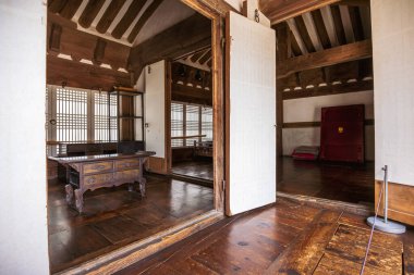 Namsangol Hanok Köyü 'nde geleneksel Kore odası. Ahşap kirişler, antika bir masa ve kafes pencereleri var. Minimalist tasarım ve doğal malzemeler sakin, kırsal bir atmosfer yaratır..