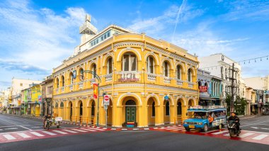 Phuket, Tayland - 10 Kasım 2024: Phuket Eski Kasabası 'ndaki tarihi Chartered Bank binası, canlı Sino-Portekiz mimarisi, açık mavi gökyüzü altında sessiz bir kavşakta duruyor.