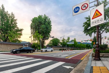 Seul, Güney Kore, 6 Temmuz 2023 - Gyeongbokgung Sarayı 'nın yakınlarındaki yaya geçidinde trafik işaretleri ve park halindeki araçlar akşam üstü gökyüzünün altında.