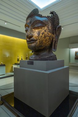 Bangkok, Tayland-2 Şubat 2025: Ulusal Bangkok Müzesi 'nde sergilenen altın kalıntılarıyla birlikte büyük bir bronz Buda lideri, Tayland ruhani sanatını ve tarihi işçiliğini gösteriyor