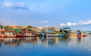 Rayong, Tayland-13 Nisan 2025: Pakistan veya Rayong Balıkçı Limanı 'na yanaşan renkli balıkçı tekneleri, canlı kıyı yaşamı ve deniz ürünleri ticareti gösteriyor.