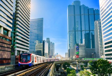 Bangkok, Tayland - 1 Ocak 2025: Sathorn Skywalk 'tan geçen BTS Skytrain, gökdelenler ve modern mimariyle çevrili, şehir ulaşımını ve iş dünyasını simgeliyor.