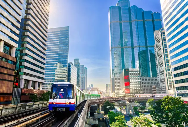 Bangkok, Tayland - 1 Ocak 2025: Sathorn Skywalk 'tan geçen BTS Skytrain, gökdelenler ve modern mimariyle çevrili, şehir ulaşımını ve iş dünyasını simgeliyor.
