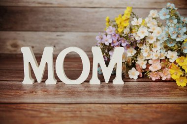 Anneler Günü 'nüz kutlu olsun. Ahşap arka planda çiçek buketi desenli.