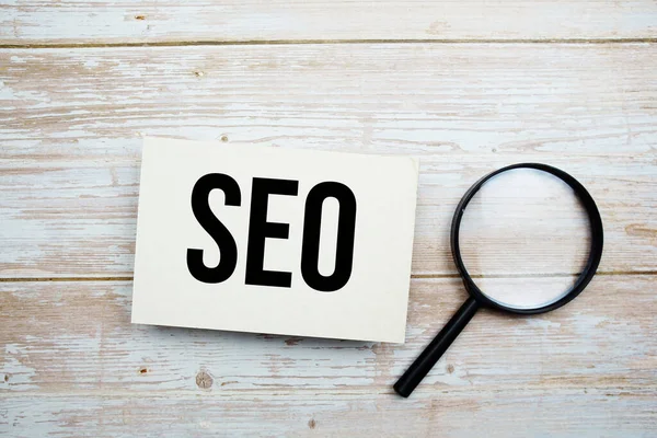 SEO metin mesajı ve büyüteçle ahşap arkaplanda boşluk kopyası