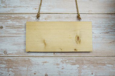 Ahşap levhanın boş yeri, halatla asılı ve ahşap zeminde yapay çiçek süslemesi.