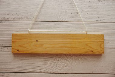 Ahşap levhanın boş yeri, halatla asılı ve ahşap zeminde yapay çiçek süslemesi.