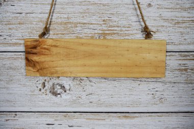 Ahşap tabelanın boş alanı ahşap arka planda iple asılı.