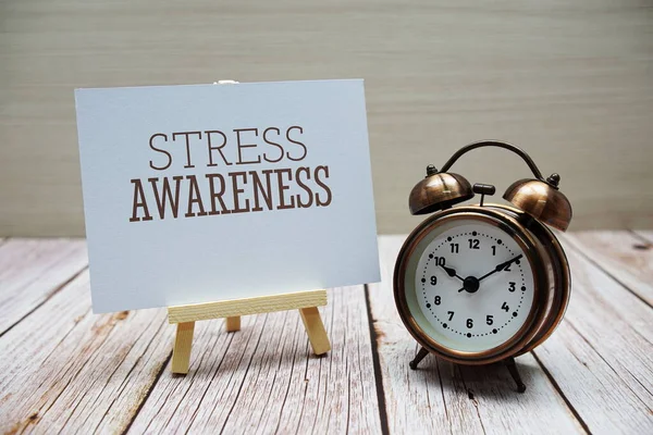 Stress Awareness word with alarm clock on wooden background