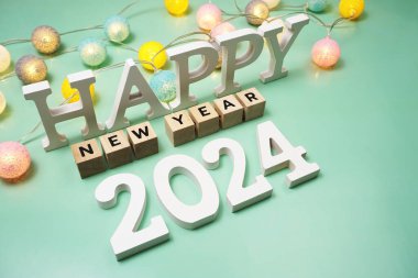 Yeşil zemin üzerinde LED pamuk topları olan yeni yıl 2024 alfabe mektubunuz kutlu olsun.