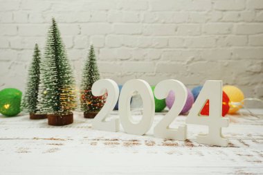 Mutlu yıllar 2024 şenlikli arka plan, beyaz tuğla duvarda Noel ağacı.