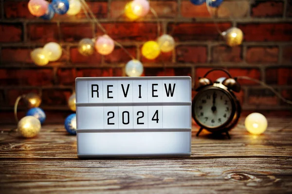 Review 2024 text in light box with alarm clock and LED cotton balls decoration