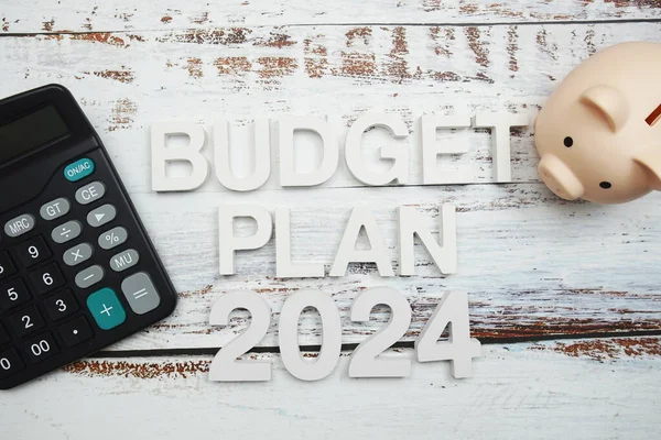 Budget Plan 2024 alphabet letter with calculator and piggy bank on wooden background