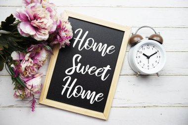 Home Sweet Home metin mesajı alarm clcok ve ahşap arka planda çiçek süslemesi
