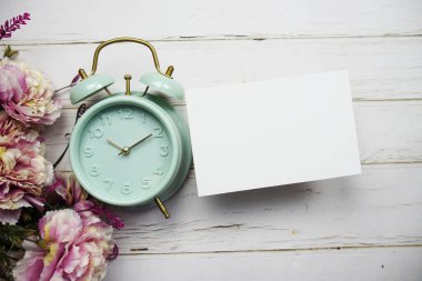 Çiçek buketi ve ahşap arka planda çalar saati olan boş kart modeli
