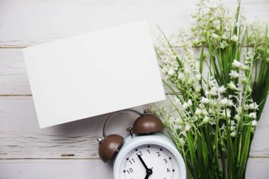 Çiçek buketi ve ahşap arka planda çalar saati olan boş kart modeli